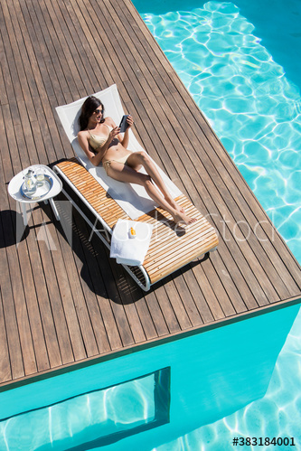 Young woman sunbathing on lounge chair at sunny poolside