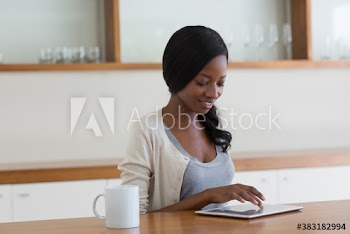 Young woman using digital tablet and drinking coffee