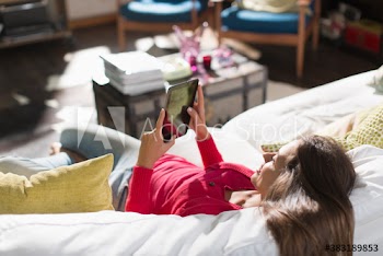Young woman using digital tablet on sunny sofa