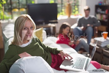 Young woman using laptop on sofa in living room with roommates