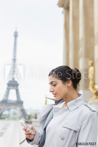 Young woman using smart phone, Eiffel Tower, Paris, France
