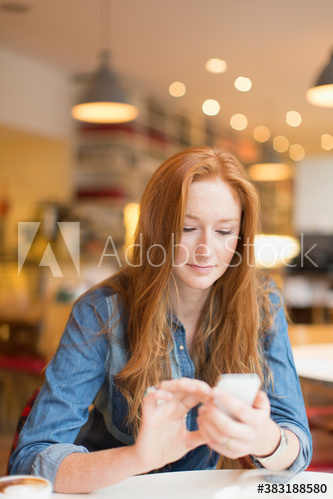 Young woman using smart phone in cafe