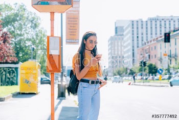 Young woman using smartphone while waiting at bus stop