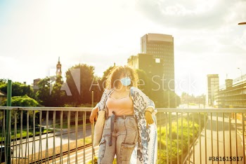 Young woman wearing medical mask leaning on railing in city