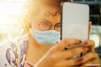 Young woman wearing medical mask taking selfie on street