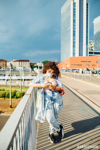 Young woman wearing medical mask using smartphone