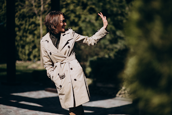 Young woman wearing trench-coat and sunglasses, posing in the city