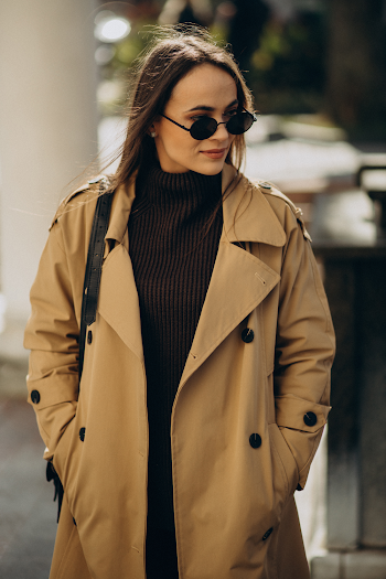 Young woman wearing trench-coat and sunglasses, posing in the city