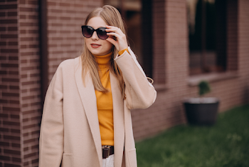 Young woman wearing trench-coat and sunglasses, posing in the city