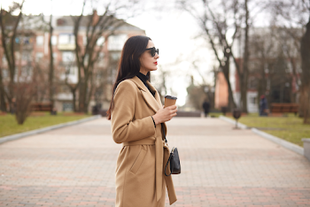 Young woman wearing trench-coat and sunglasses, posing in the city