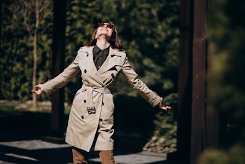 Young woman wearing trench-coat and sunglasses, posing in the city
