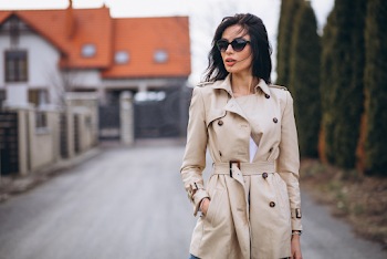 Young woman wearing trench-coat and sunglasses, posing in the city