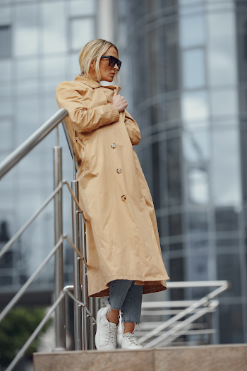 Young woman wearing trench-coat and sunglasses, posing in the city