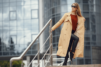 Young woman wearing trench-coat and sunglasses, posing in the city
