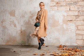 Young woman wearing trench-coat and sunglasses, posing in the city