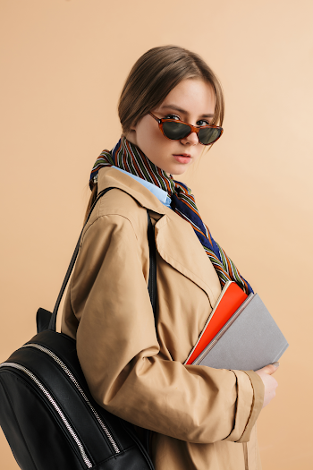 Young woman wearing trench-coat and sunglasses, posing in the city