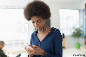 Young woman with afro texting with smart phone