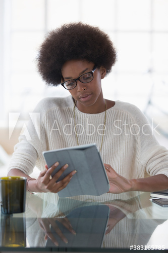 Young woman with afro using digital tablet working from home