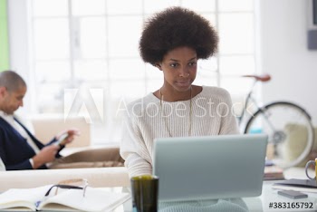 Young woman with afro working from home at laptop