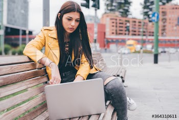Young woman working on laptop while sitting on bench