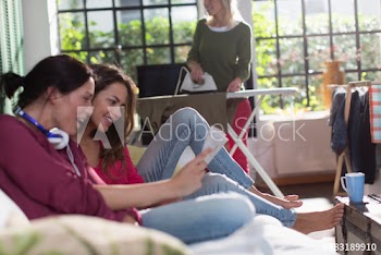 Young women friends reading magazine on sofa