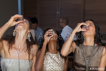 Young women friends taking tequila shots at party