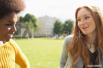 Young women friends talking in sunny park
