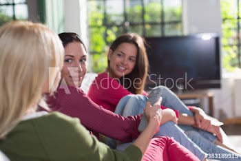 Young women friends watching TV on sofa