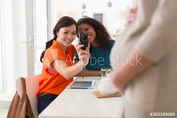 Young women with camera photographing pregnant friend