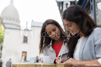 Young women writing postcards at sidewalk cafe, Montmartre, Paris