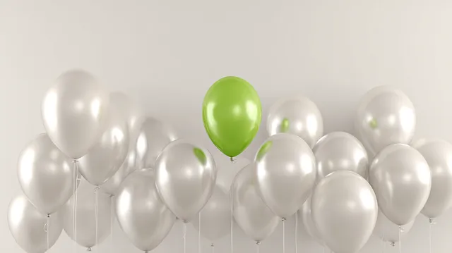 Colorful Celebration: Green Balloon Among Silver Ones